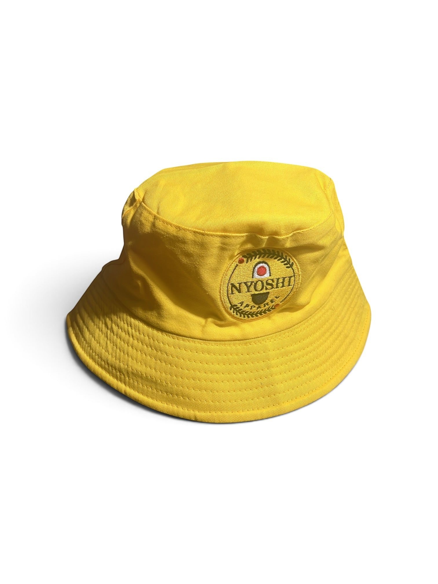 Shop Nova Finds reversible yellow bucket hat with embroidered Nyoshi Apparel logo patch on a white background